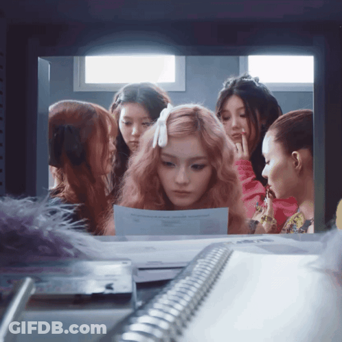 A Group Of Girls Are Looking At A Piece Of Paper That Says ' A ' On It GIF