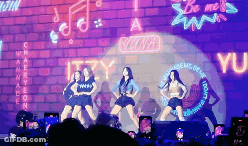 A Group Of Girls Are Performing In Front Of A Neon Sign That Says Wannabe GIF
