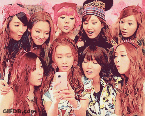 A Group Of Girls Are Posing For A Picture With One Girl Holding A Cell Phone GIF