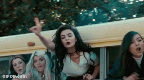 A Group Of Girls Are Riding On The Back Of A School Bus And One Girl Is Pointing At The Camera . GIF
