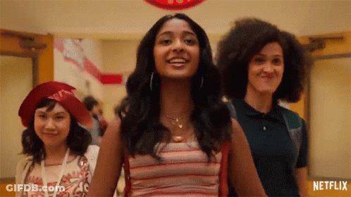 A Group Of Girls Are Standing In A Hallway Holding Hands And Smiling . GIF