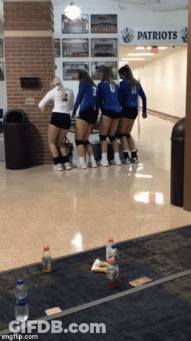 A Group Of Girls Are Standing In A Hallway Under A Patriots Sign GIF