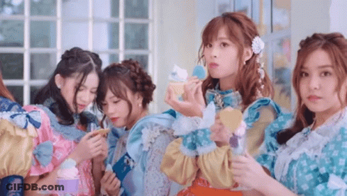 A Group Of Girls Are Standing Next To Each Other And One Of Them Is Holding A Cupcake . GIF