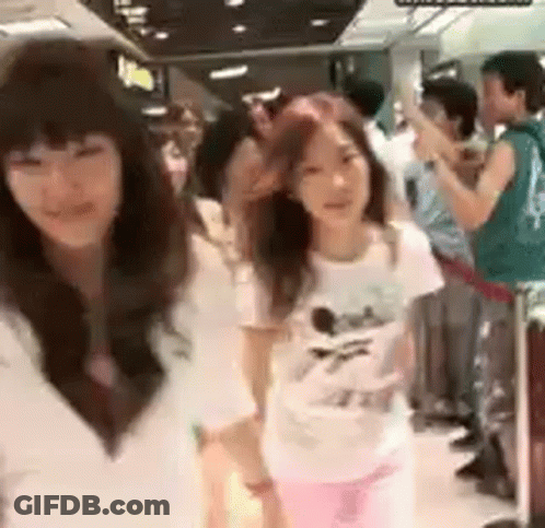A Group Of Girls Are Standing Next To Each Other In A Crowded Room . GIF