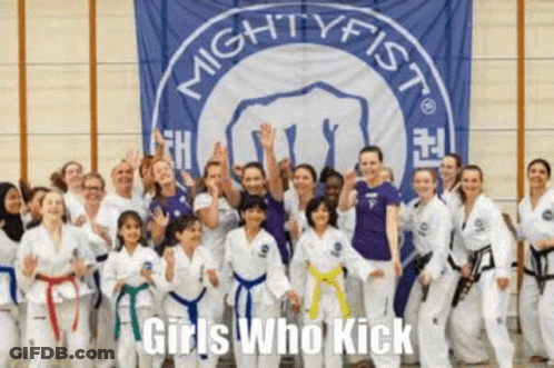 A Group Of Girls In Karate Uniforms Are Posing For A Picture In Front Of A Banner That Says `` Girls Who Kick '' . GIF