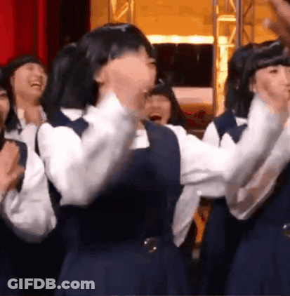 A Group Of Girls In School Uniforms Are Standing In A Room And Laughing . GIF