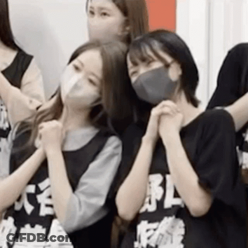 A Group Of Girls Wearing Face Masks Are Standing Next To Each Other . GIF