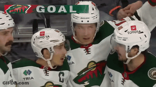 A Group Of Hockey Players Are Celebrating A Goal With A Banner That Says Goal GIF