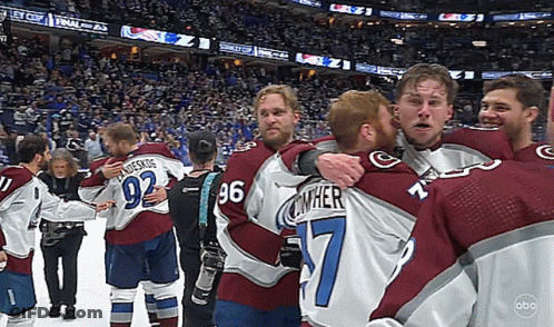 A Group Of Hockey Players Are Hugging Each Other Including Number 7 GIF