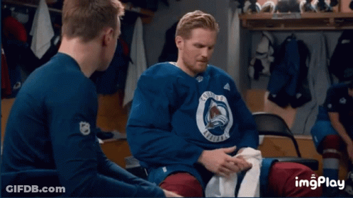 A Group Of Hockey Players Are Sitting In A Locker Room With The Colorado Avalanche Logo On A Wall GIF