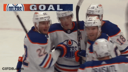 A Group Of Hockey Players Celebrate A Goal With A Banner That Says Goal GIF