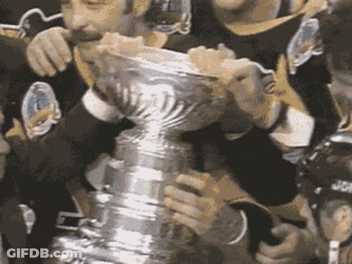 A Group Of Hockey Players Holding A Trophy With The Letter T On It GIF