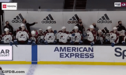 A Group Of Hockey Players Sit In Front Of A Wall That Says American Express On It GIF