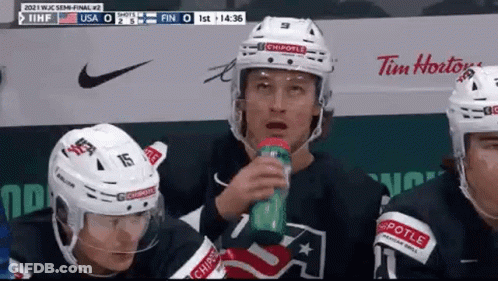 A Group Of Ice Hockey Players Are Sitting On The Bench Drinking Water . GIF