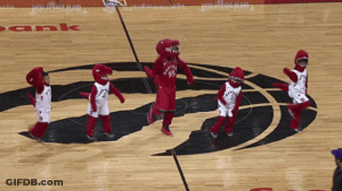 A Group Of Kids Dressed As Raptors Mascots Are Dancing On The Court GIF
