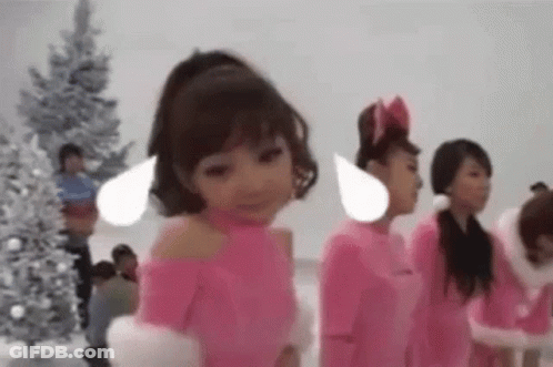 A Group Of Little Girls In Pink Costumes Are Standing Next To Each Other In Front Of A Christmas Tree . GIF