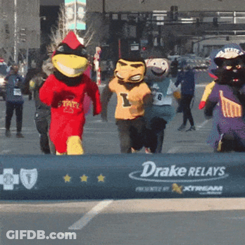 A Group Of Mascots Are Running Past A Drake Relays Sign GIF