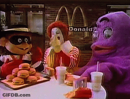 A Group Of Mcdonald 'S Mascots Are Sitting At A Table With Hamburgers And Drinks GIF