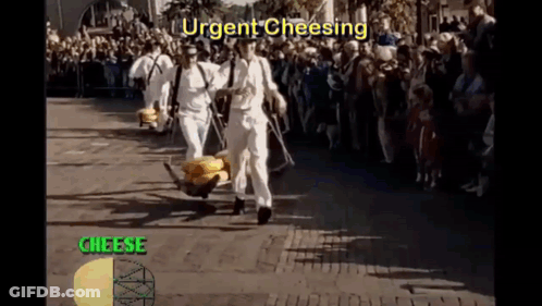 A Group Of Men Are Carrying A Bunch Of Cheese On A Cart While A Crowd Watches GIF
