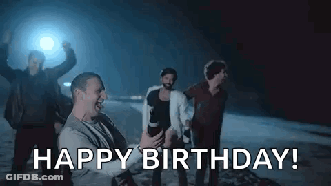 A Group Of Men Are Celebrating A Birthday With A Man Holding A Camera And Saying `` Happy Birthday '' . GIF