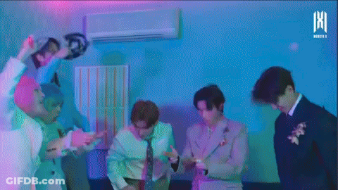 A Group Of Men Are Dancing In A Room With A Purple Light Behind Them . GIF