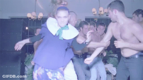 A Group Of Men Are Dancing In A Room With A Woman In A Purple Dress GIF