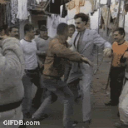 A Group Of Men Are Dancing In A Room With Clothes Hanging On A Rack GIF