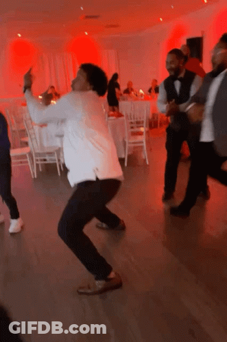 A Group Of Men Are Dancing In A Room With Red Lights Behind Them GIF