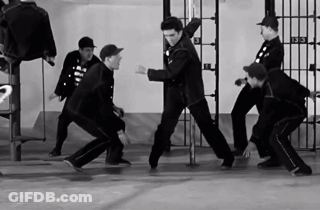 A Group Of Men Are Dancing In Front Of A Prison Cell With The Number 3 On It GIF