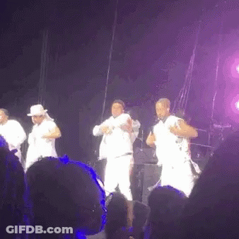 A Group Of Men Are Dancing On A Stage In Front Of A Crowd At A Concert . GIF