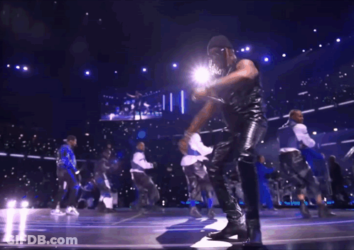 A Group Of Men Are Dancing On A Stage In Front Of A Large Screen GIF