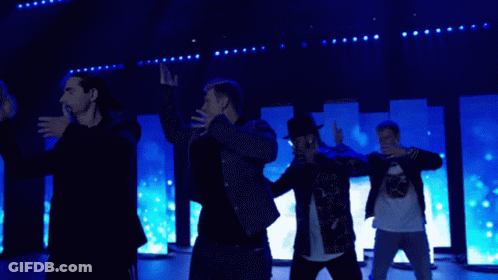 A Group Of Men Are Dancing On A Stage In Front Of Blue Lights GIF