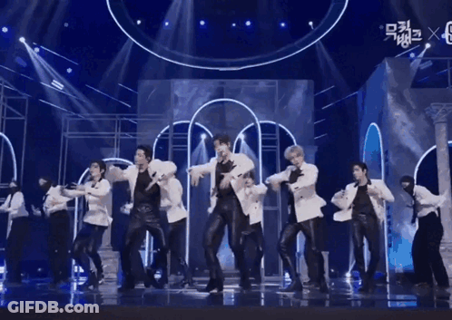 A Group Of Men Are Dancing On A Stage With A Blue Background . GIF