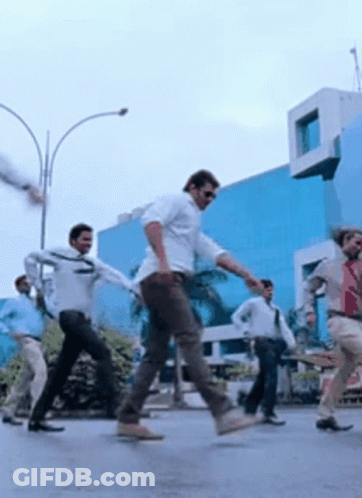 A Group Of Men Are Dancing On A Street In Front Of A Building . GIF