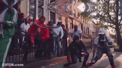 A Group Of Men Are Dancing On The Sidewalk In Front Of A Building . GIF