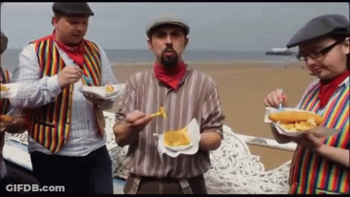A Group Of Men Are Eating French Fries On A Bench GIF