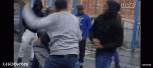 A Group Of Men Are Fighting On A Street In A Video . GIF