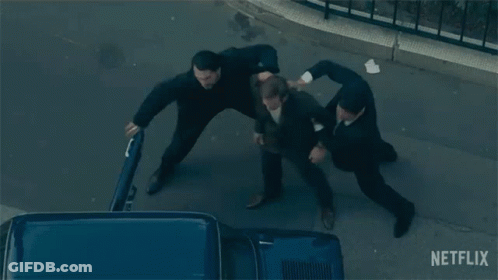 A Group Of Men Are Fighting On A Street With A Netflix Logo In The Background GIF