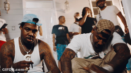 A Group Of Men Are Gathered In A Room And One Of Them Is Wearing A Hat That Says Gucci GIF