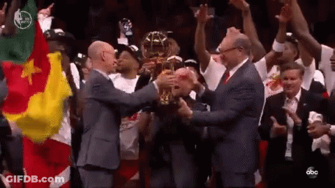 A Group Of Men Are Holding A Trophy In A Stadium . GIF