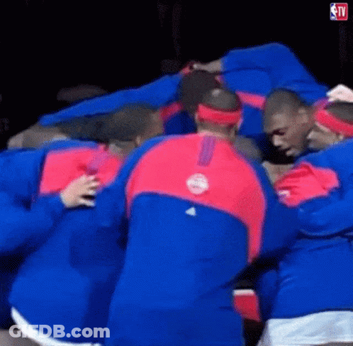 A Group Of Men Are Huddled Together In A Huddle . GIF