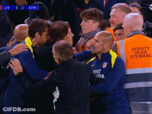 A Group Of Men Are Huddled Together With One Wearing An Atm Shirt GIF
