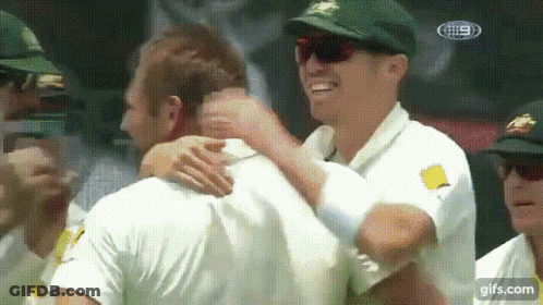 A Group Of Men Are Hugging Each Other In A Crowd . GIF
