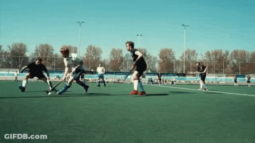 A Group Of Men Are Playing A Game Of Field Hockey On A Field GIF
