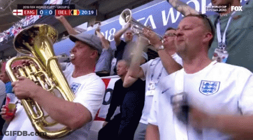 A Group Of Men Are Playing Brass Instruments In A Stadium During A Soccer Game . GIF