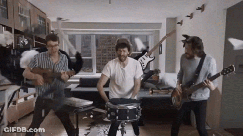 A Group Of Men Are Playing Instruments In A Living Room Including A Drummer GIF