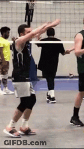 A Group Of Men Are Playing Volleyball On A Court And One Of Them Is Dancing . GIF