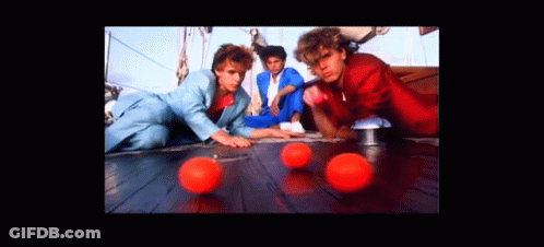 A Group Of Men Are Playing With Red Balls On A Wooden Floor GIF