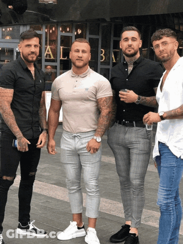 A Group Of Men Are Posing For A Picture In Front Of A Building That Has The Letter A On It GIF
