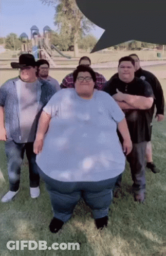 A Group Of Men Are Posing For A Picture With One Of Them Being A Very Large Man GIF